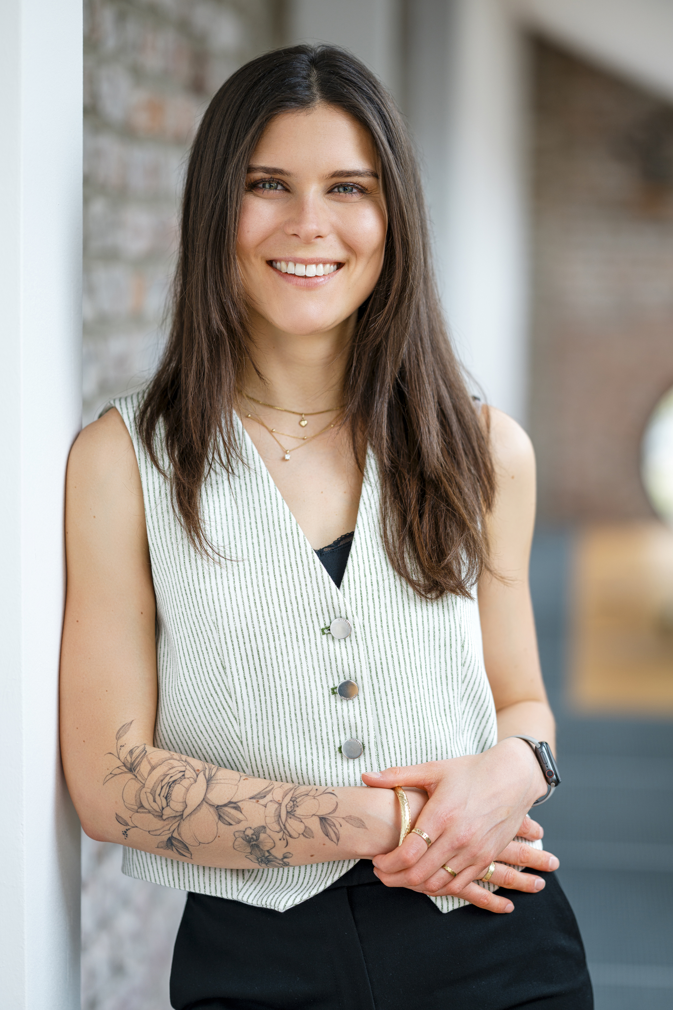Paula Wüllner - Portraitfoto vor neutralem Hintergrund, lächelnd, mit verschränkten Armen